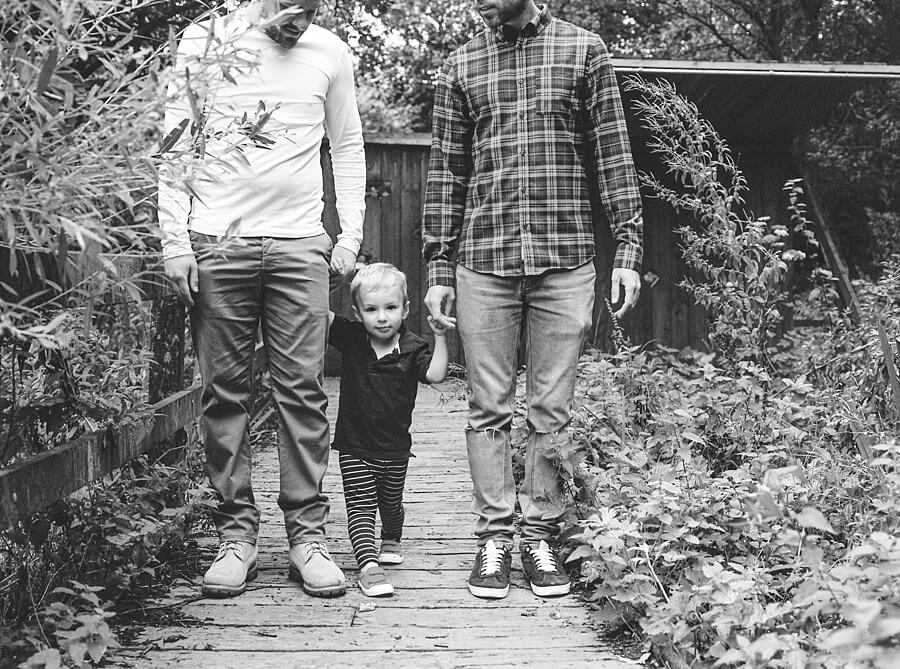 Black and white picture of child holding hands with adults in the woods | Family Woodland Shoot